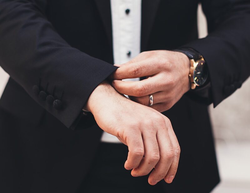 A man's hands adjusting the cuffs of his black suit