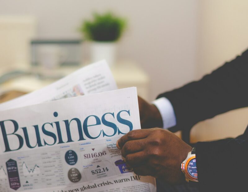 person wearing suit reading business newspaper